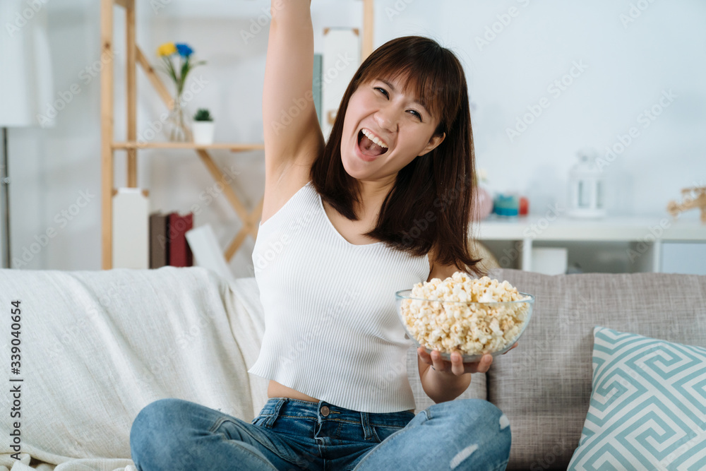 快乐的中国女士举起手，在客厅里观看奥运会，激动不已。beauti