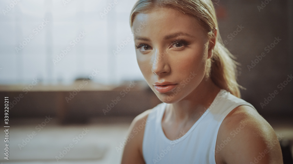 Close-up Portrait of Beautiful Strong Fit Blond Sitting in a Loft Industrial Gym with Motivational P