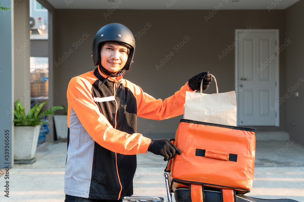 亚洲外卖员身穿橙色制服，准备在顾客面前发送外卖食品袋