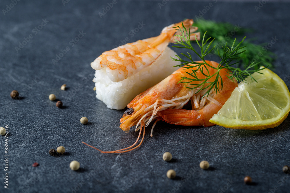 Boiled shrimp  as an ingredient for ebi sushi with lemon and dill on a stone board