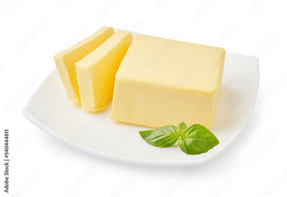 Sliced butter of piece butter on the white plate with basil leaves isolated on white background.