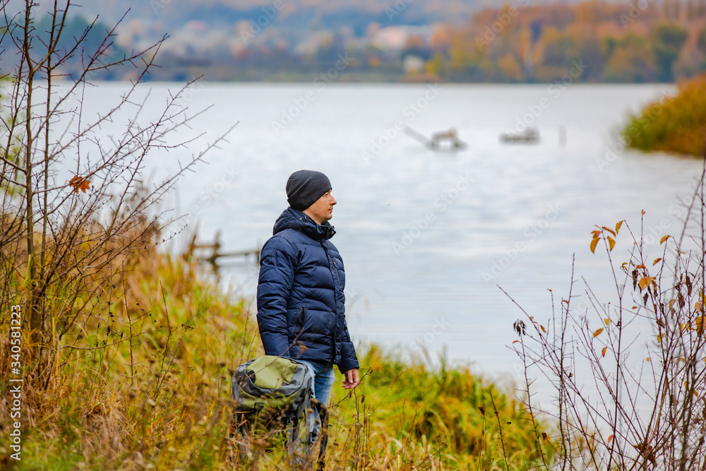 秋天，一个背着背包的游客走在河边。一场美丽的自然景观