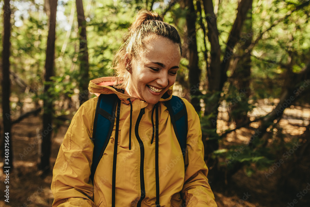 Woman with backpack standing in forest and smiling