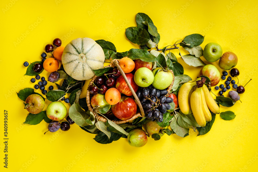 Flat-lay of fresh fruits and berries on yellow background