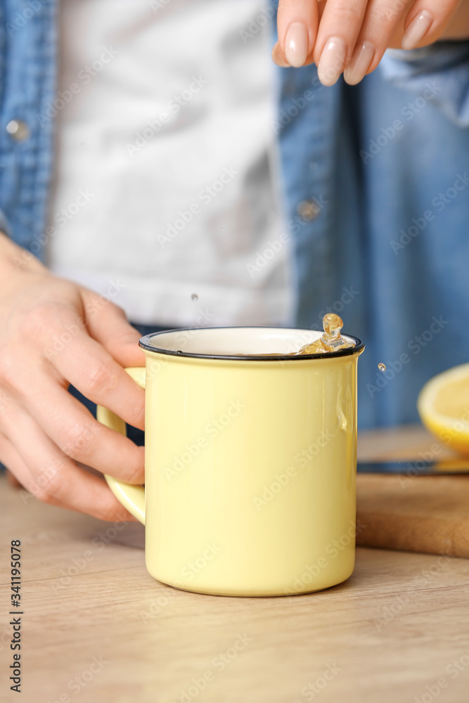 Beautiful young woman making tea with lemon at home, closeup