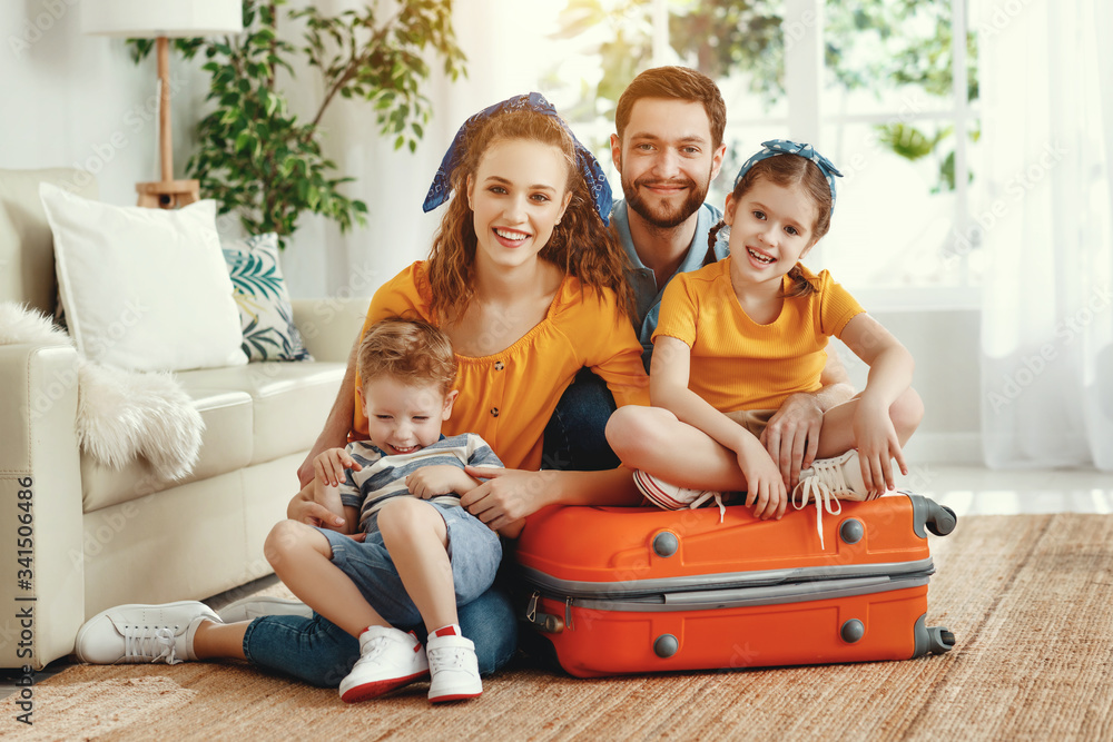 快乐的一家人，行李箱放在地板上看着相机