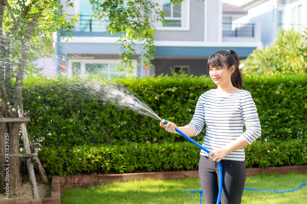 亚洲女子在家后院的避暑花园里玩得很开心，花园软管泼水触犯法律