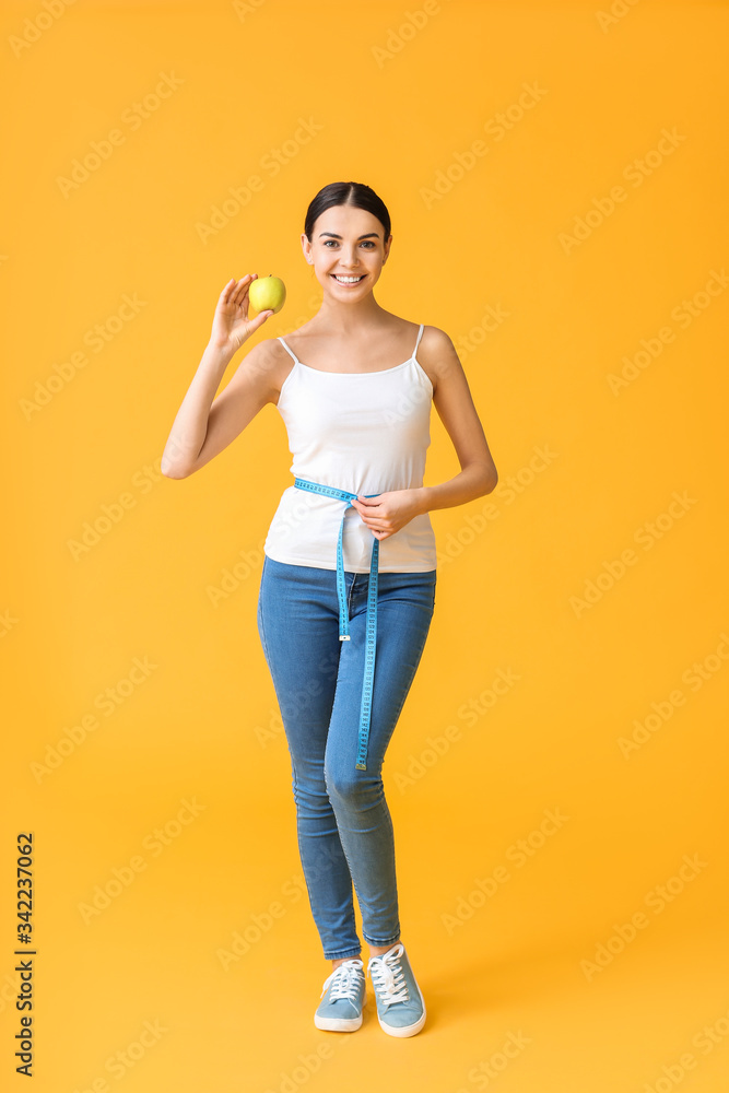 年轻女性，带着卷尺和彩色背景的苹果。减肥概念