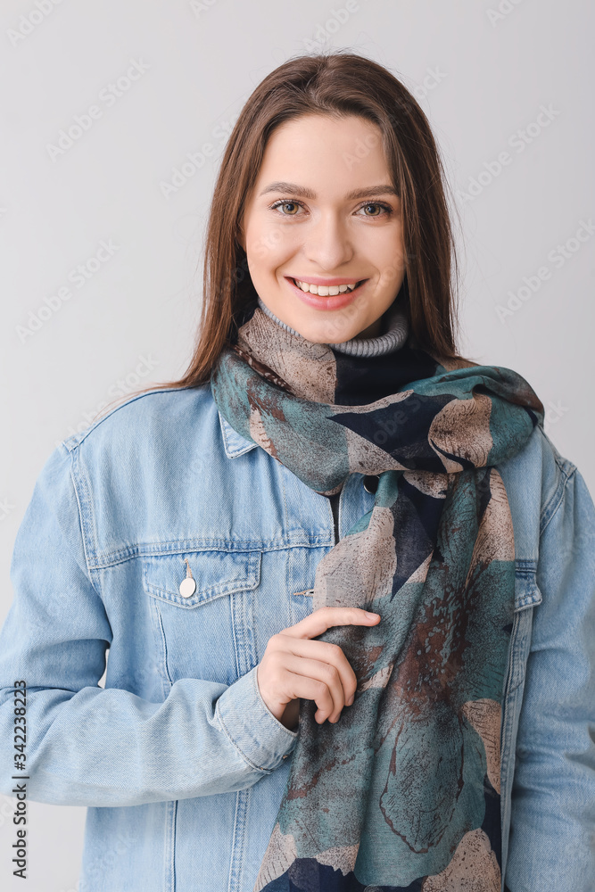 漂亮的年轻女人，灰色背景上戴着时尚的围巾