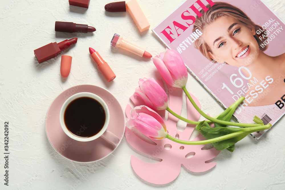 Cup of coffee, fashion magazine, flowers and cosmetics on light background
