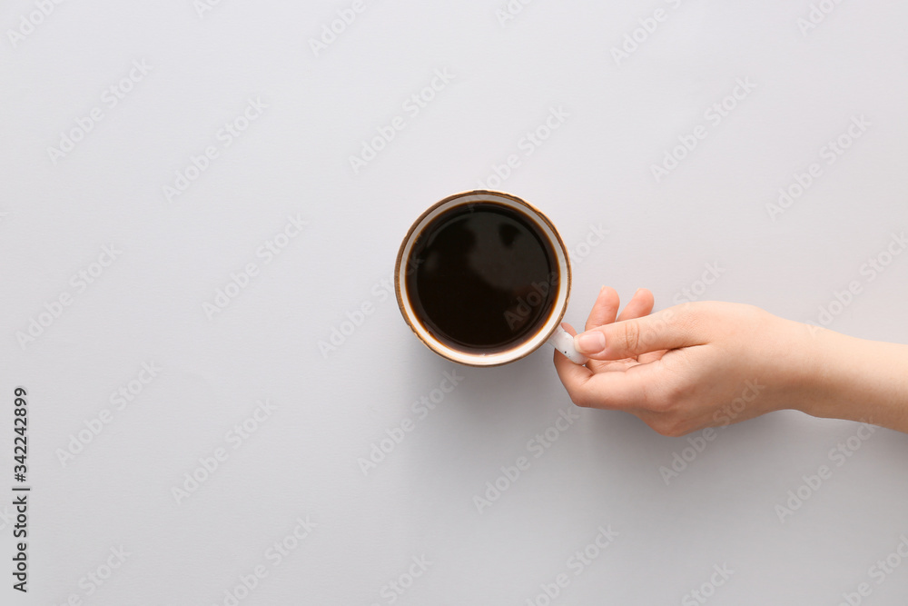 女性手拿着一杯淡背景的热咖啡，俯视图