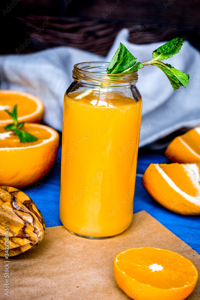 切橙子，瓶子里装果汁，厨房背景上放薄荷