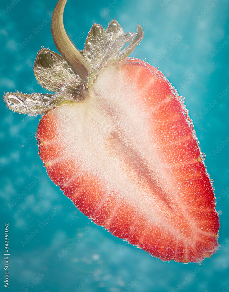 一半红色成熟草莓，蓝色背景中有一个气泡。特写。