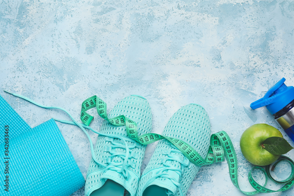 瑜伽垫、运动鞋、彩色背景的水瓶和苹果。减肥概念