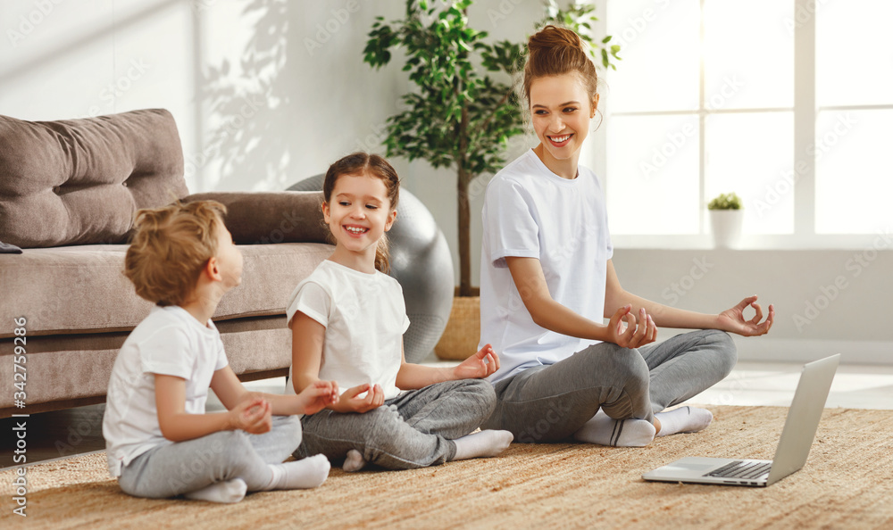 Smiling woman with children meditating on floor at home.