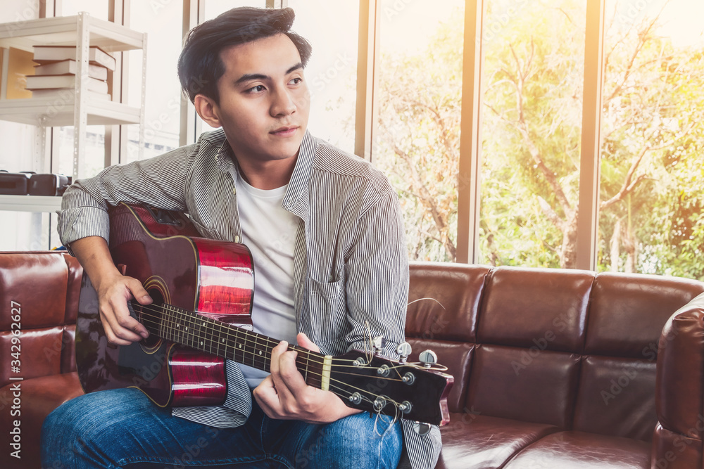 年轻的吉他手在家里拿着吉他。音乐和歌曲概念。