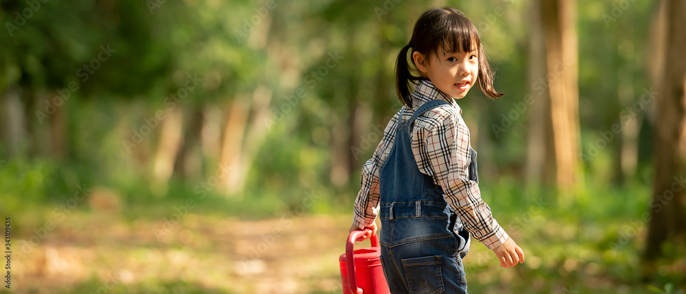 快乐可爱的亚洲小女孩拿着喷壶走进公园