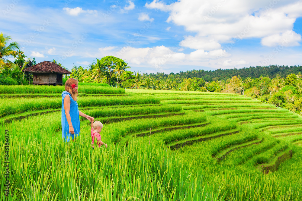 巴厘岛传统田野美景。大自然漫步在绿色的水稻露台上。幸福的母亲抱着