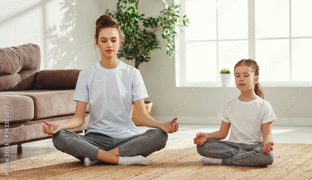 Calm girl with mother meditating at home