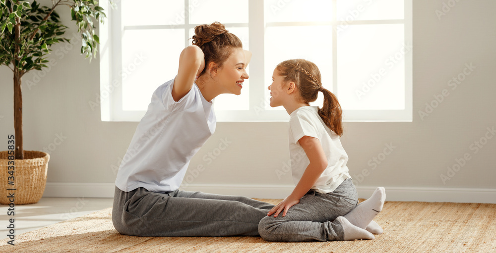 Fit mother and daughter training together at home.