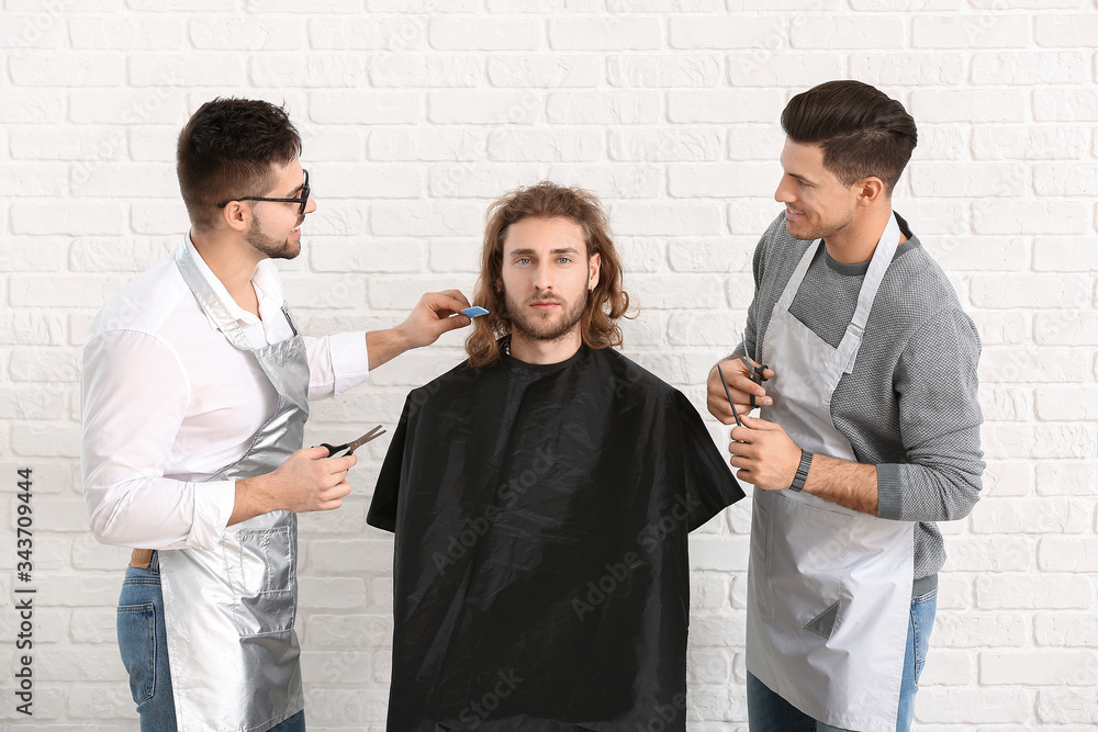 年轻理发师在白砖背景下与客户合作