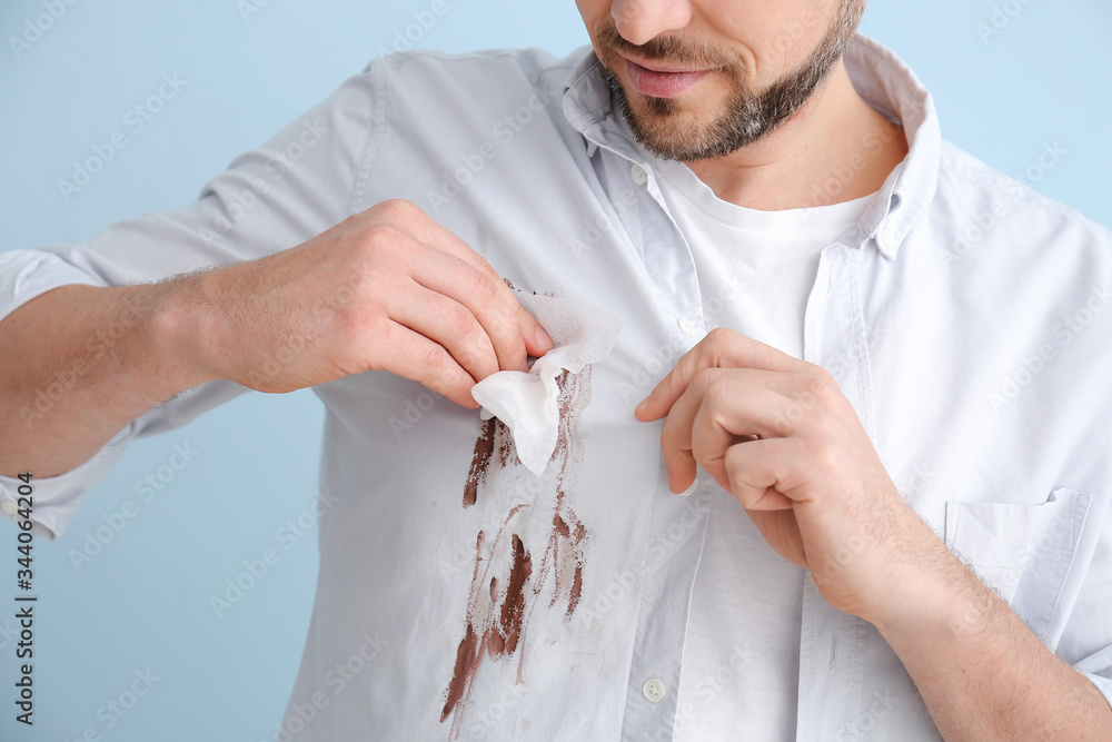 男子在彩色背景上擦拭衣服上的污垢