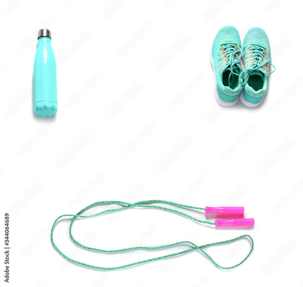 Sport shoes, bottle of water and jumping rope on white background