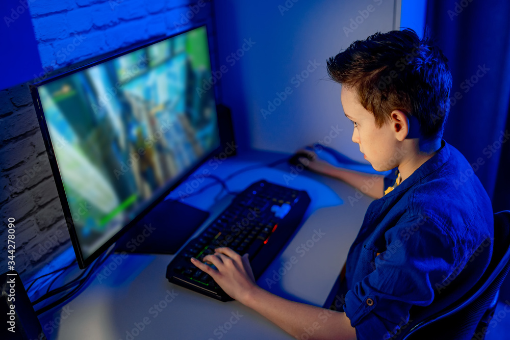 小男孩在家玩电子游戏。严肃的青少年在电脑前。沉迷于视频游戏