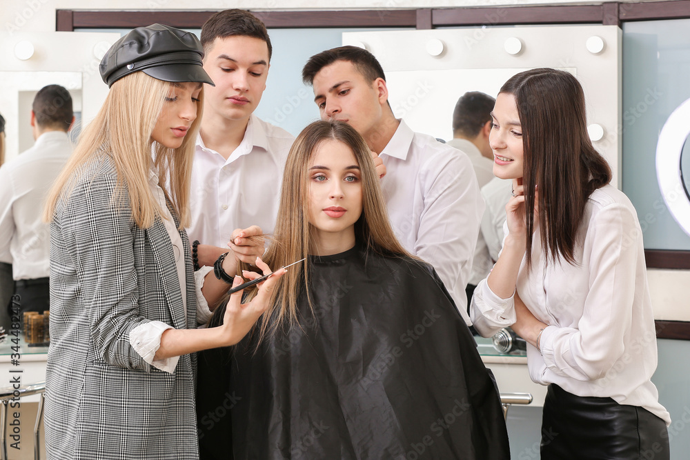 Professional hairdresser teaching young people in salon