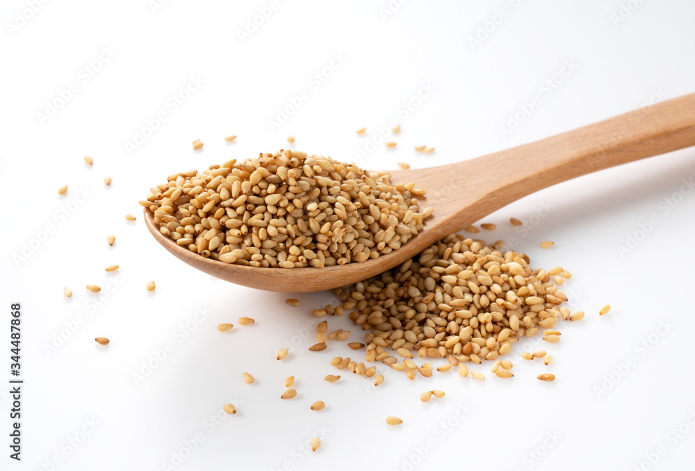 White sesame seeds in a wooden spoon placed on a white background