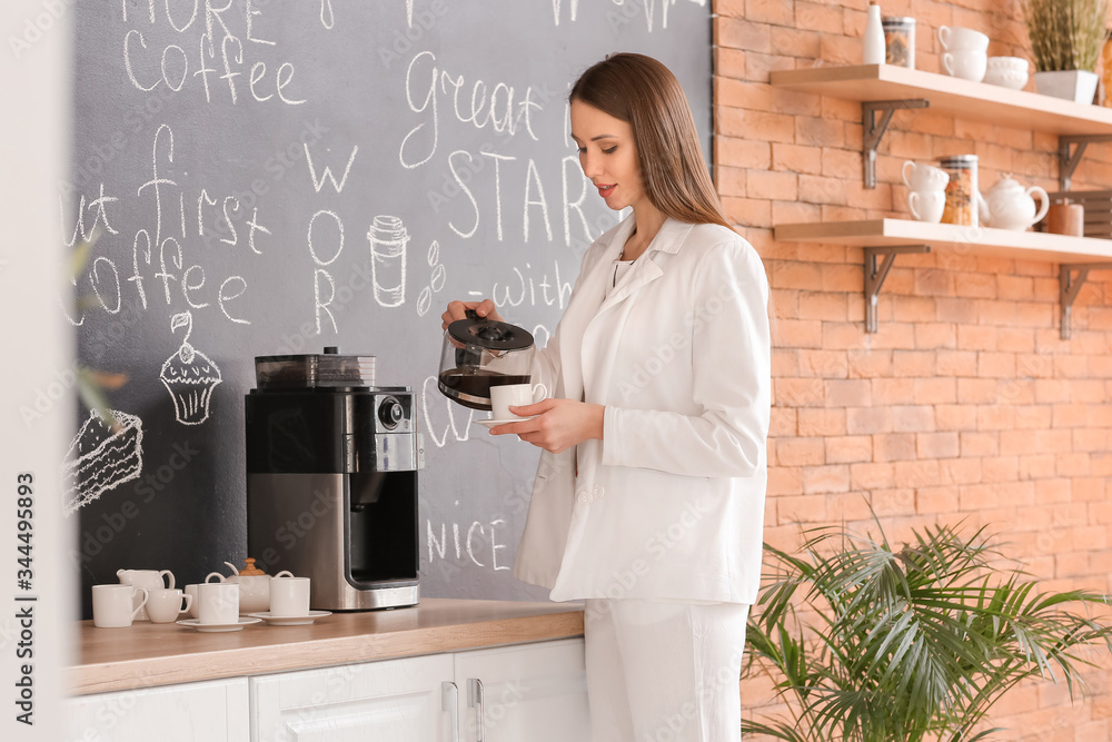 Young businesswoman drinking coffee in kitchen of office