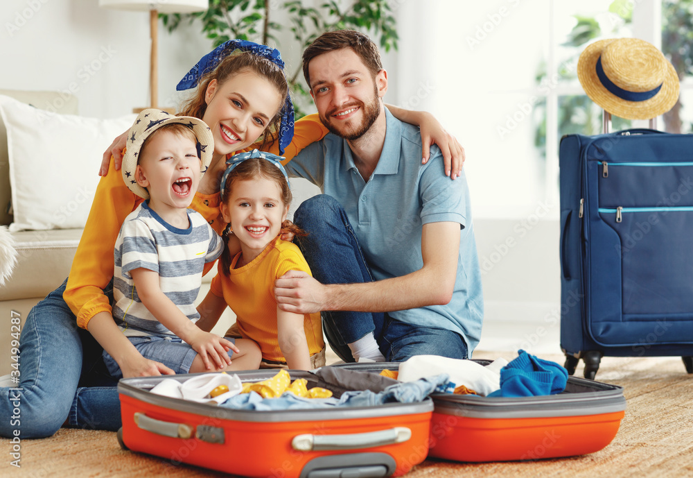 快乐的一家人，行李箱放在地板上看着相机。