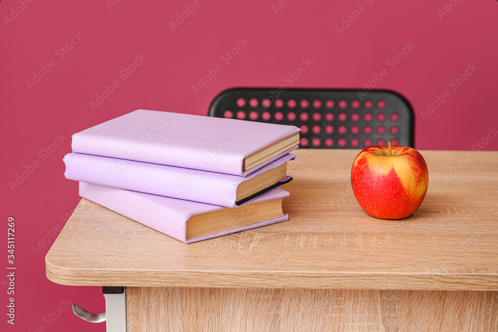 彩色背景下学校桌子上的书和苹果