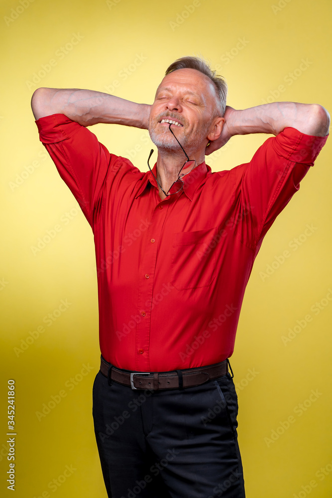 英俊的中年老人，穿着红色衬衫，背景为孤立的黄色。放松和str