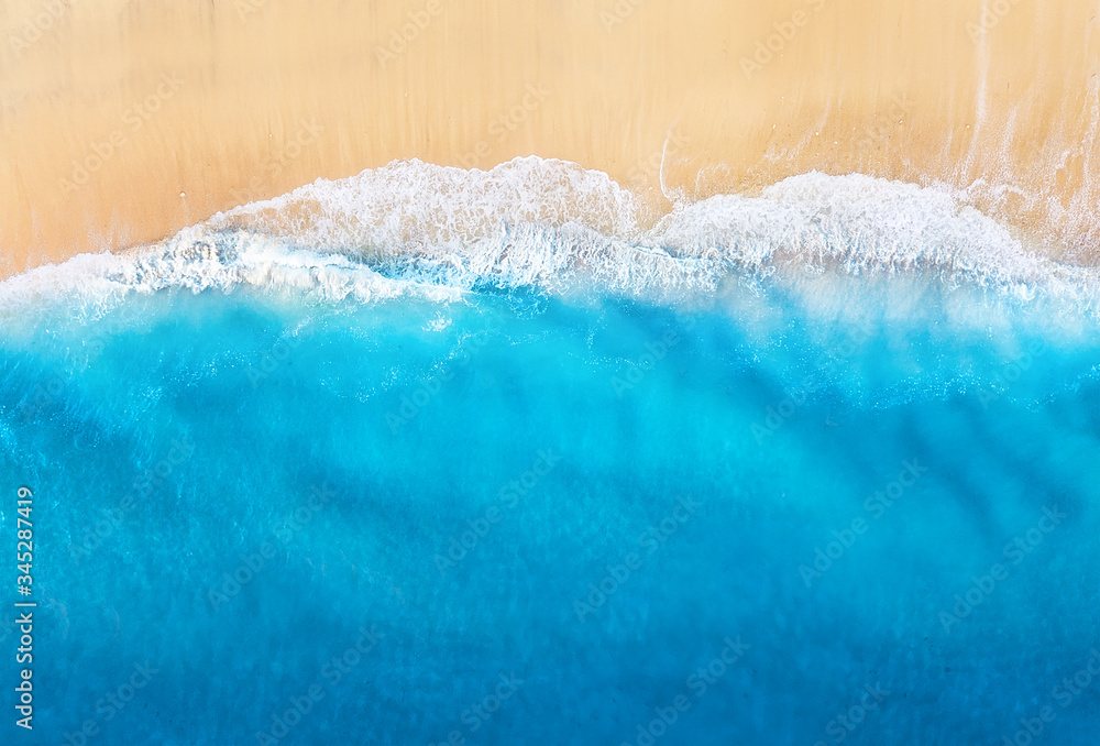 Coast with waves as a background from top view. Blue water background from drone. Summer seascape fr