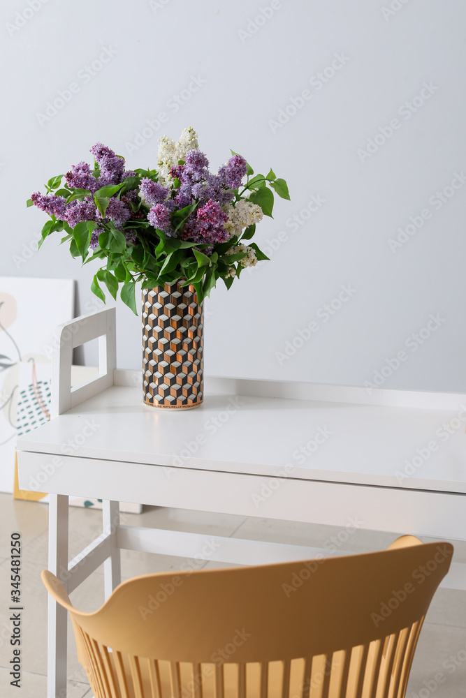 房间灰色墙壁附近的桌子上有美丽的淡紫色花朵
