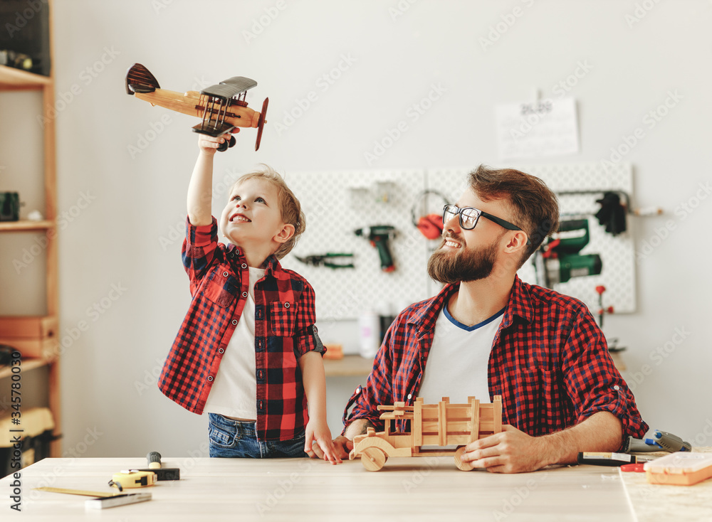 Happy man with son playing handmade wooden toys in workshop.