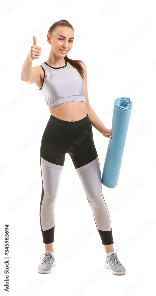 穿着瑜伽垫的运动型年轻女子在白色背景下展示拇指向上的姿势
