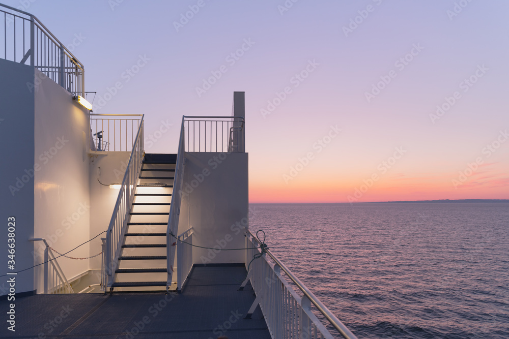 日落时的游轮甲板。傍晚时平静的海洋和晴朗的粉红色天空。游轮度假