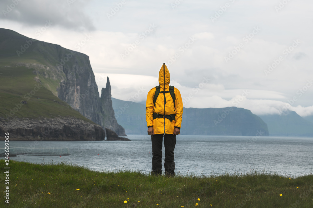 在女巫手指悬崖附近的Trollkonufingur视点，穿着有趣的黄色夹克的游客。Vagar岛