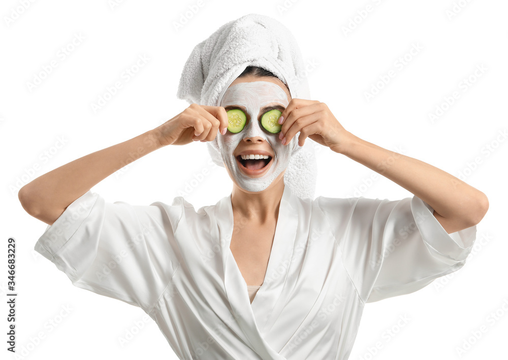 Beautiful young woman with cucumber slices and facial mask on white background