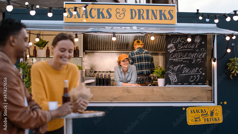 Food Truck Female Employee Smiles and Looks at the Camera. Street Food Truck Selling Burgers in a Mo