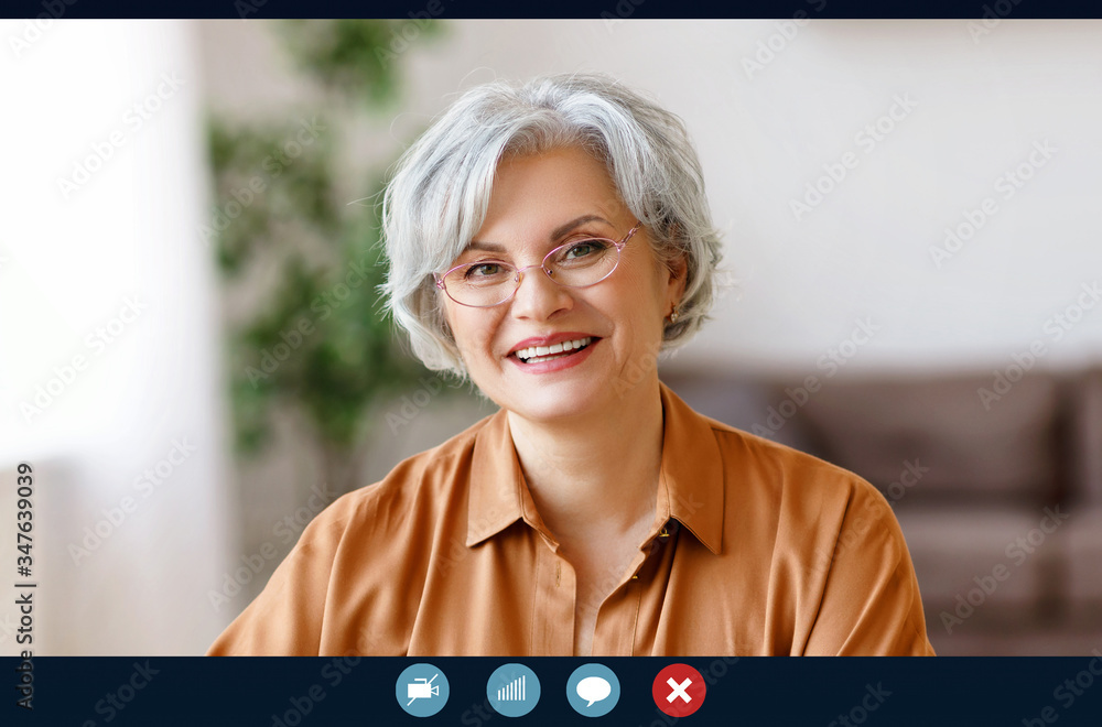 快乐的老年妇女坐在家里与亲戚视频通话，