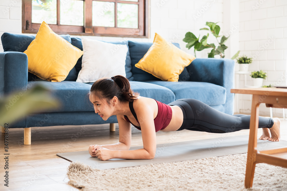 年轻的亚洲健康女性在家锻炼，锻炼，健身，做瑜伽，家庭健身概念