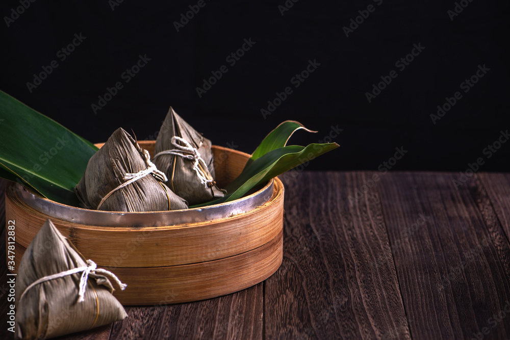 粽子——木制桌子上蒸笼里的中国粽子——黑色复古背景代表龙
