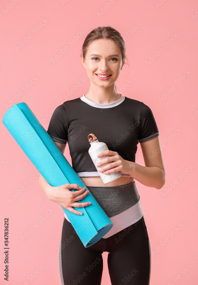 Sporty young woman with yoga mat and bottle of water on color background