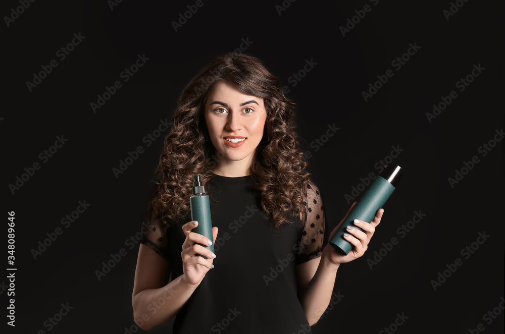 Beautiful young woman with hair sprays on dark background