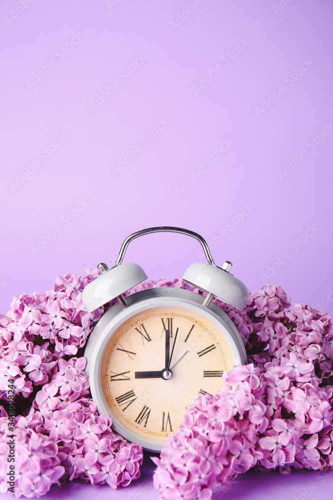 彩色背景上的闹钟和花朵。春天的时间