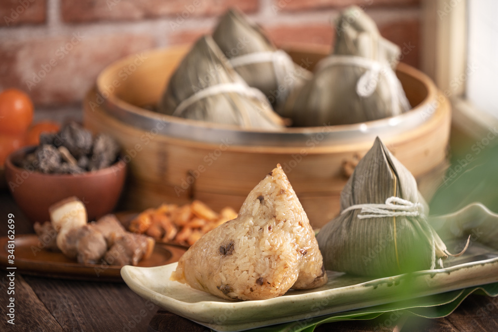 Zongzi - Chinese rice dumpling zongzi in a steamer on wooden table with red brick, window background