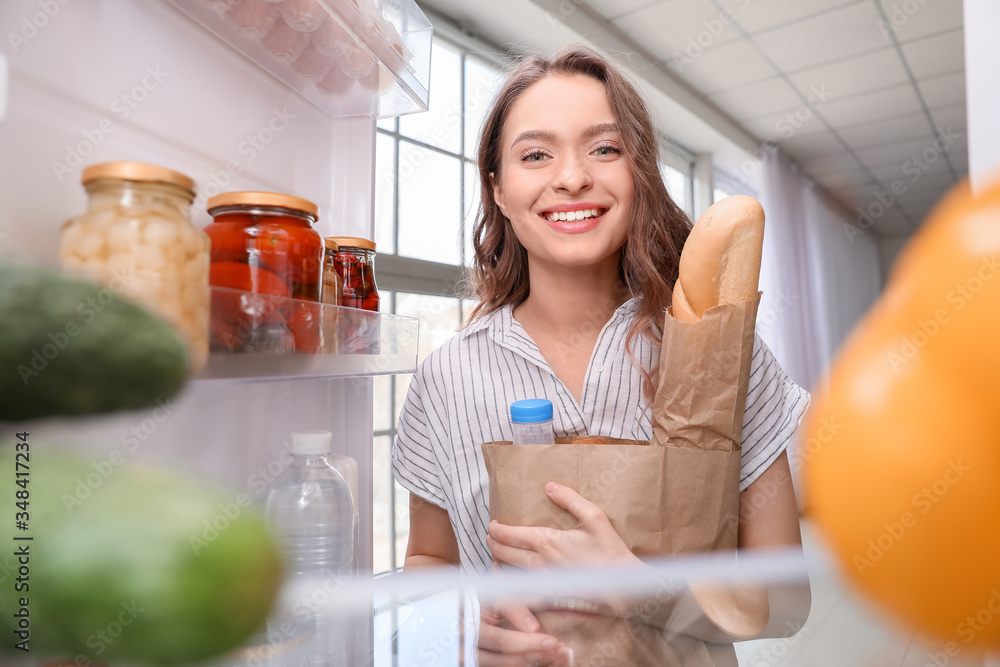 年轻女子在厨房里打开市场上的新鲜产品，从冰箱里看